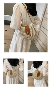 Detail view of woven straw bucket bag with brown leather strap and buckle on model