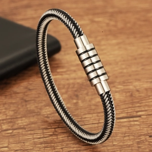 Braided steel wire men's bracelet with silver magnetic industrial clasp on wooden table