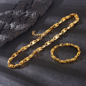 Gold geometric link chain necklace and bracelet set on dark stone background