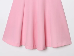 Close-up of pink halter dress hem showing refined woven fabric and detailed stitching