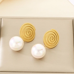 Close-up of golden spiral texture earrings with white pearls in a beige jewelry box