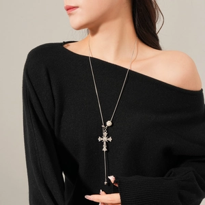 Silver cross pendant necklace with round bead detail worn by a model on black top