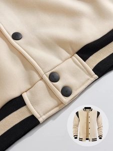 Close-up of beige varsity jacket featuring black and yellow striped ribbed hem and collar