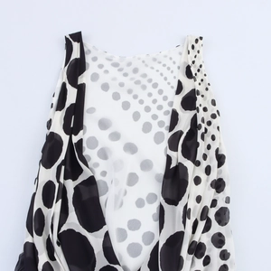 Dettaglio del top leggero in chiffon a pois bianchi e neri con scollatura drappeggiata