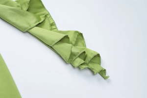 Detail of grass green pleated ruffles and fine stitching on a slim fit fashion garment