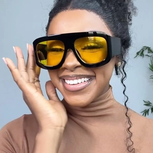 Close-up of oversized square sunglasses with black frames and vibrant yellow lenses