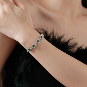 Gros plan d'un bracelet argenté avec pierre émeraude carrée au poignet d'une femme