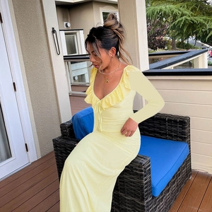 Detail of light yellow slim fit dress featuring a deep V-neck and ruffled edges