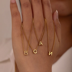 Detail showing multiple 26 English letter pendants in gold on a stainless steel cable chain