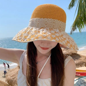 Close-up of a women's yellow woven straw sun hat decorated with white lace floral accents