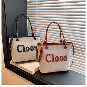 Detail of canvas tote bags with Cloos lettering and leather trim in black and brown colors