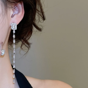 Close-up of sparkling cubic zirconia square tassel earrings on model