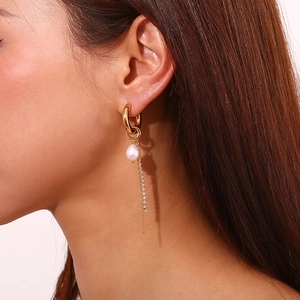 Close-up of golden tassel earring with white freshwater pearl and zircon star drop