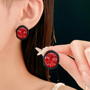 Vue détaillée de boucles d'oreilles géométriques avec centre rouge et cadre noir mat