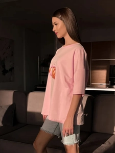 Λεπτομέρεια ροζ βαμβακερού t-shirt με ανάγλυφη στάμπα και χαμηλωμένους ώμους