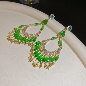 Détail de boucles d'oreilles vintage avec perles émeraude et pompons scintillants