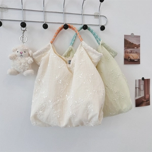 Close-up of floral embroidery on canvas tote bags with woven handles and snap button