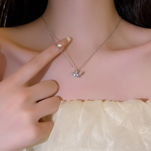 Elegant angel wing heart necklace with silver finish and white zircon stones on model