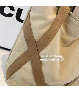 Close-up of neat stitching and brown woven handle on a beige canvas tote bag