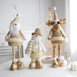 Three gold and white Christmas plush dolls with reindeer and snowman on a tabletop