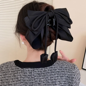 Détail d'une élégante pince à cheveux en satin noir avec de longs rubans fluides et soyeux