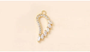 Macro detail of gold wing pendant with white marquise zircons and metal connection ring