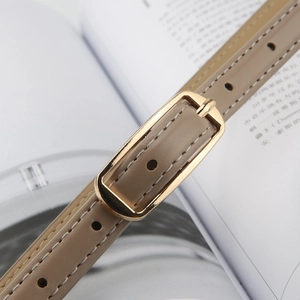 Detailed close-up of light brown leather belt with elegant golden rectangular buckle