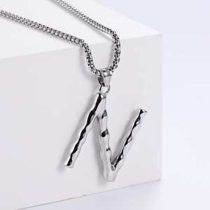 Détail macro du pendentif lettre N argentée avec texture sur une chaîne à billes