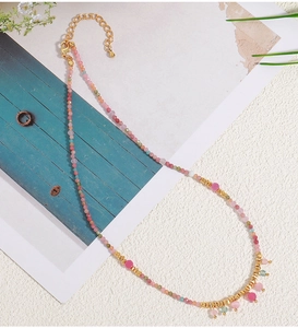 Detail of handmade beaded necklace with pink and green stones and gold lobster clasp