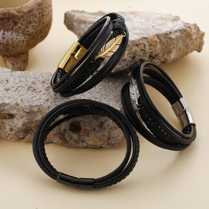 Detailed macro view of multilayered black leather bracelets with gold and silver feathers