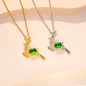 Detailed close-up of emerald green deer pendants in gold and silver finish with rhinestones