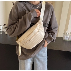 Detail of beige woven leather chest bag showing texture and wide shoulder strap