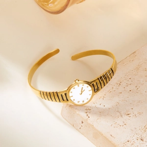 Elegant gold open cuff watch with white dial on stone base for a luxury minimalist style