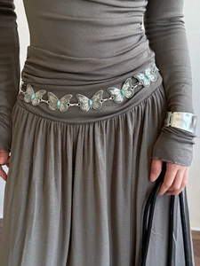 Close-up of silver butterfly waist chain with turquoise stones on a model's dress