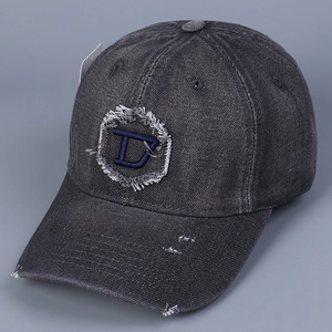Dettaglio del cappellino da baseball in denim grigio scuro con toppa D ricamata