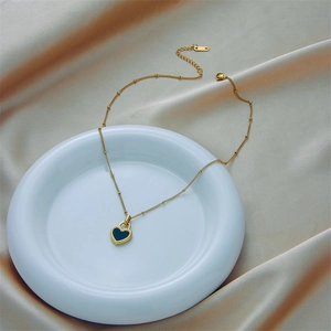 Elegant gold heart pendant necklace on white ceramic tray with champagne silk background