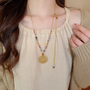 Détail du collier de perles en agate grise avec pendentif boucle de paix en jade poli