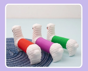 Three colorful unicorn pop tube fidget toys in red, purple, and green on a blue mat