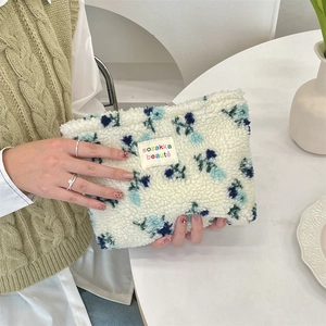 Detail of soft teddy velvet makeup bag featuring blue floral patterns and zip closure