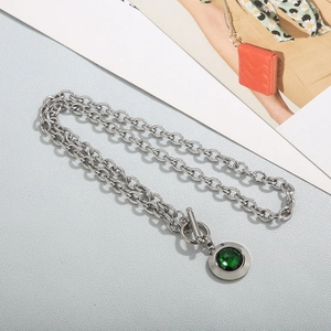Detailed shot of a silver toggle clasp necklace featuring a large green faceted crystal pendant