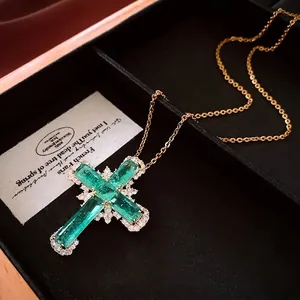Collier croix vintage en or avec pierres d'émeraude et zircons dans un écrin à bijoux