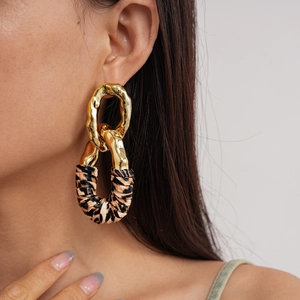 Close-up of golden irregular lava texture ring with leopard print wrap earring detail