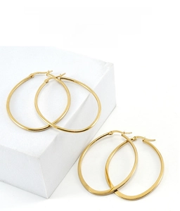 Close-up of elegant 18K gold-plated oval hoop earrings on white geometric display