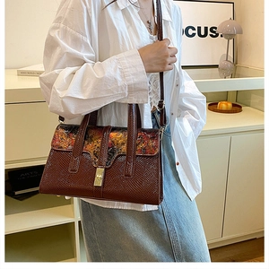 Detail of vintage brown lizard texture handbag with artistic floral flap and gold clasp