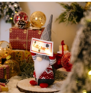 Glow-in-the-dark Christmas gnome plush holding a welcome sign amidst festive decor
