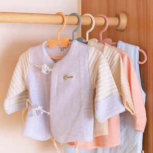 Kids waffle knit cotton tops in soft colors hanging on minimalist bow-style hangers