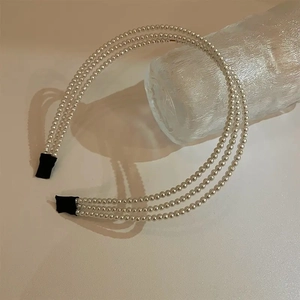 Detail shot of the vintage triple-row faux pearl headband with elegant fabric wrapped ends