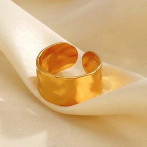 Irregular wide gold-plated stainless steel ring on silk fabric with hammered texture