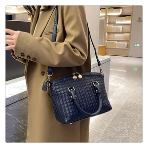 Détail du sac à main tissé bleu marine avec bandoulière porté sur un manteau