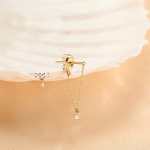 Detail of S925 silver gold-plated turquoise tassel chain earrings on a white shell